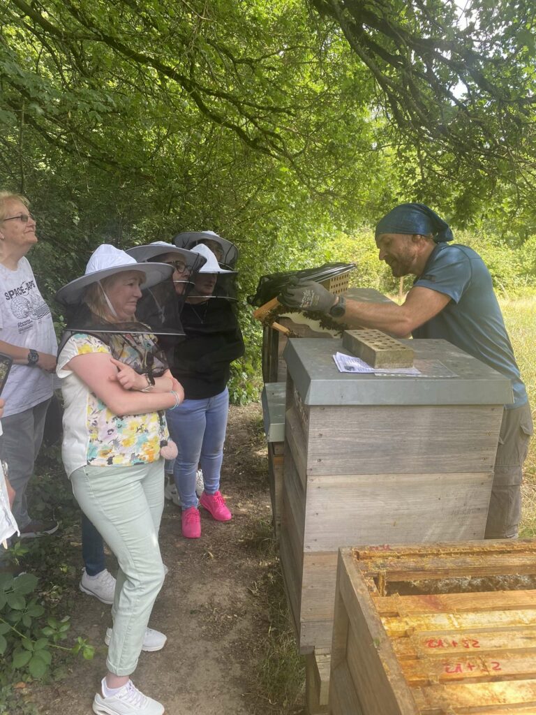 Schnuppertag am Bienenstand. Kursleiter und verschleierte Gäste am Bienenstand.